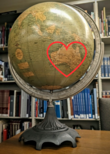 a photograph of a globe with a red heart drawn around australia
